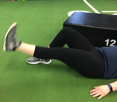 woman lifting one leg while laying down